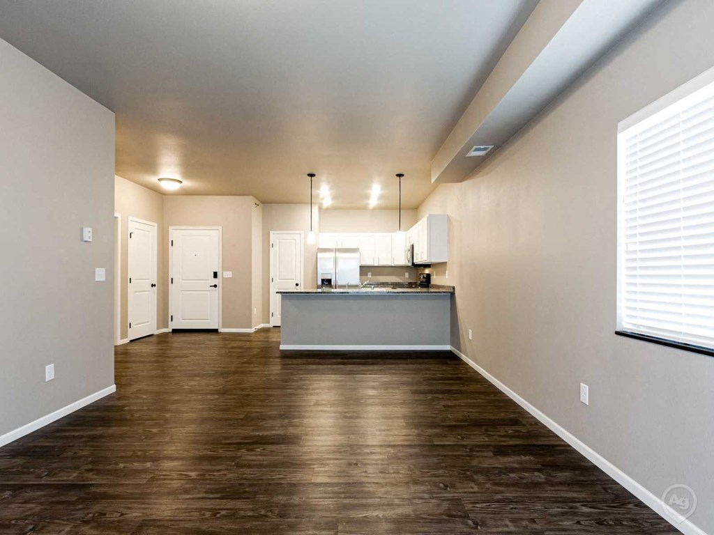 an empty living room and kitchen with wood flooring