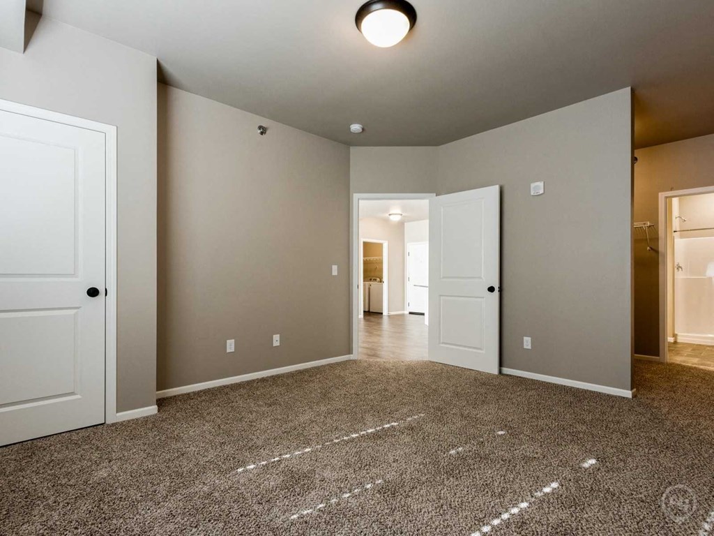 an empty living room with white doors and a carpeted floor