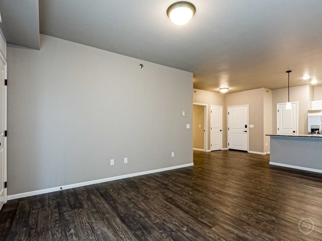 the living room and kitchen of an empty home with wood flooring