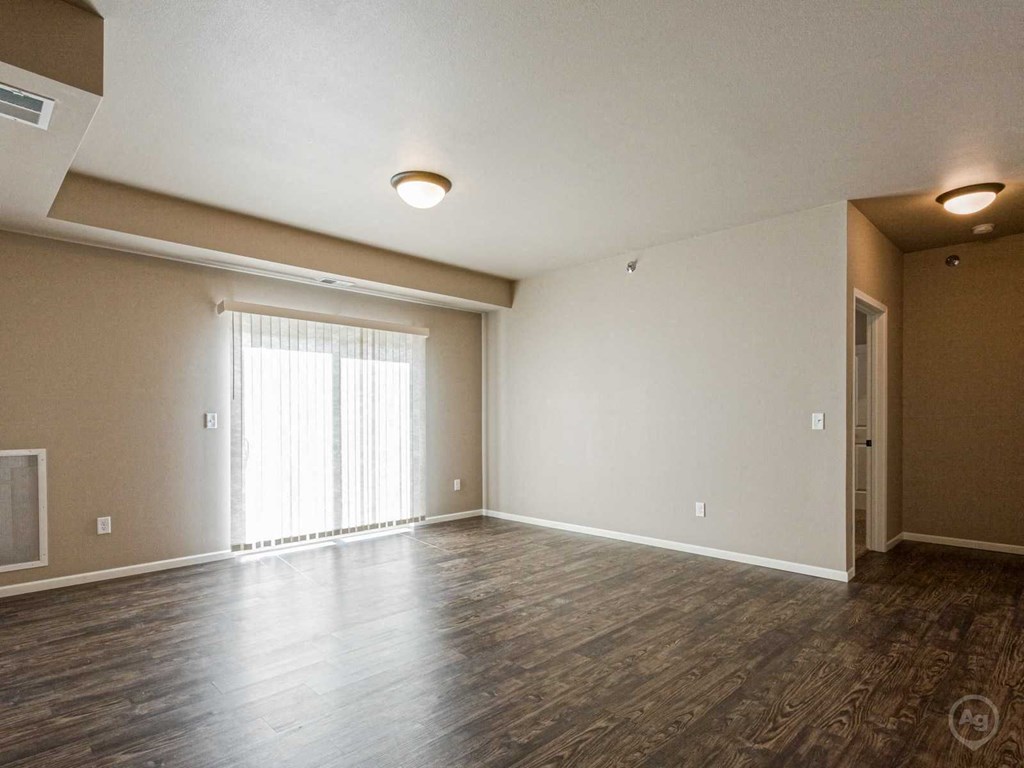 an empty living room with wood flooring and a window