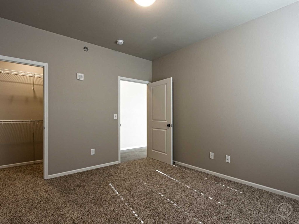 a bedroom with a door to a closet and a carpeted floor