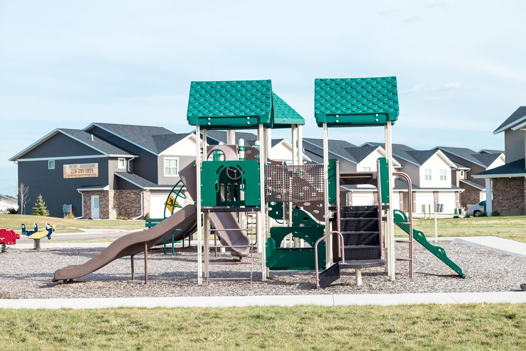 a playground with a swing set in front of a group of houses