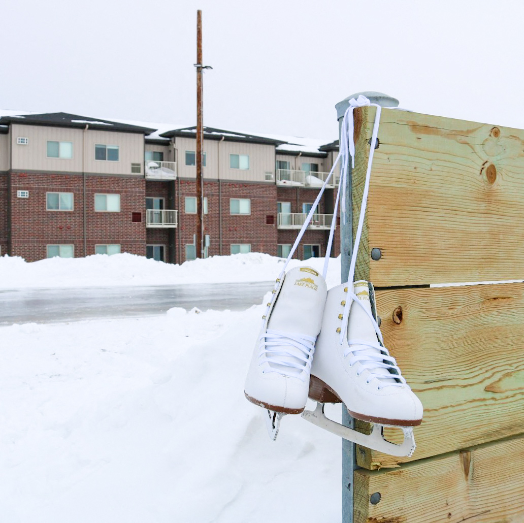 a pair of ice skates hanging on a wooden fence in the snow