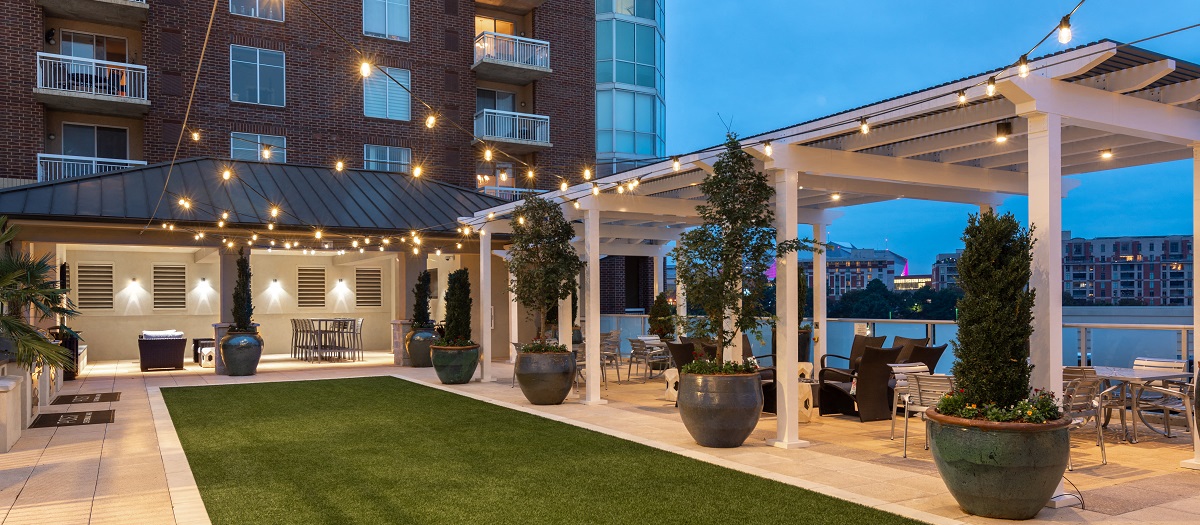 a patio with a lawn and a building with lights on it