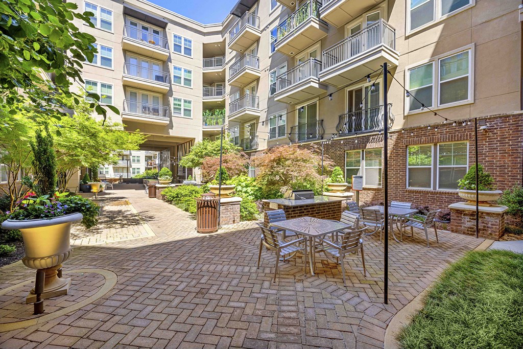 a courtyard with tables and chairs in front of an apartment building