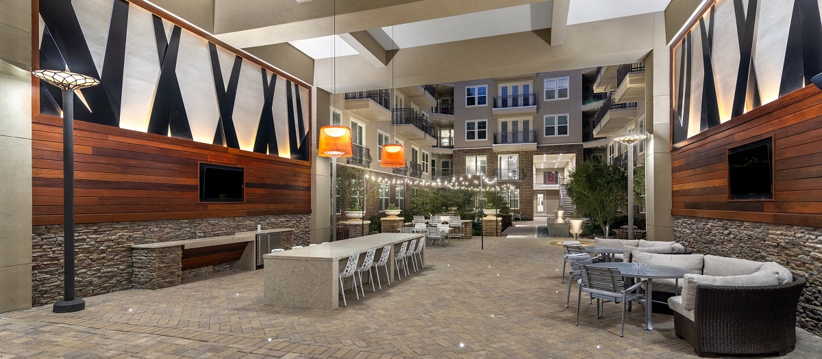 a courtyard with tables and chairs and a building in the background