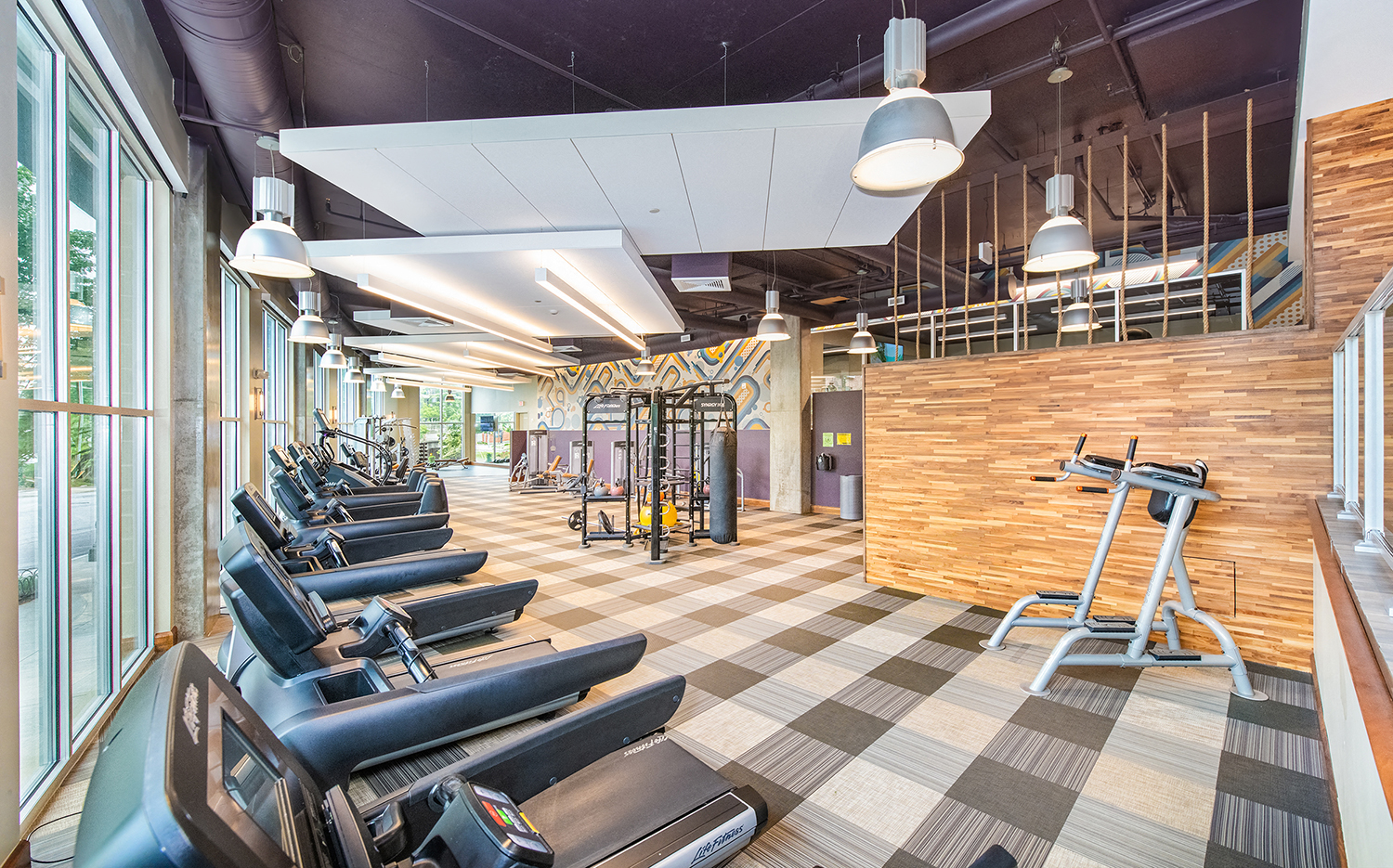 a gym with cardio machines and chairs and a wall of windows
