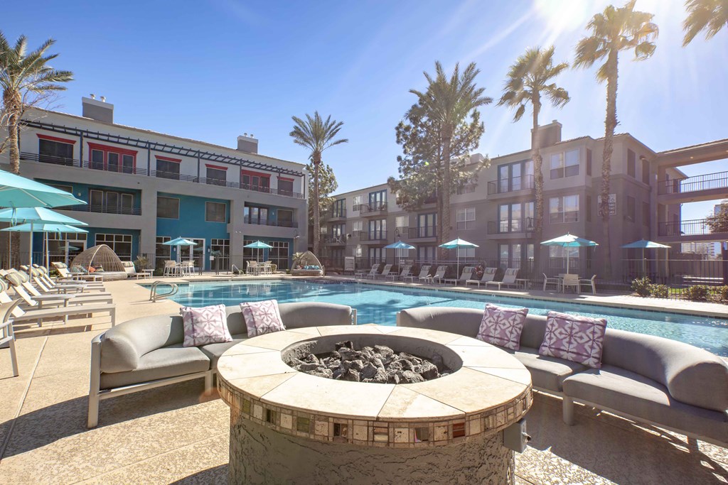 a swimming pool with chairs and a fire pit in front of a building