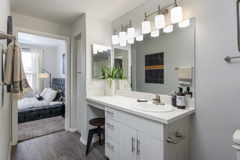 a bathroom with a sink and a mirror and a bedroom with a couch