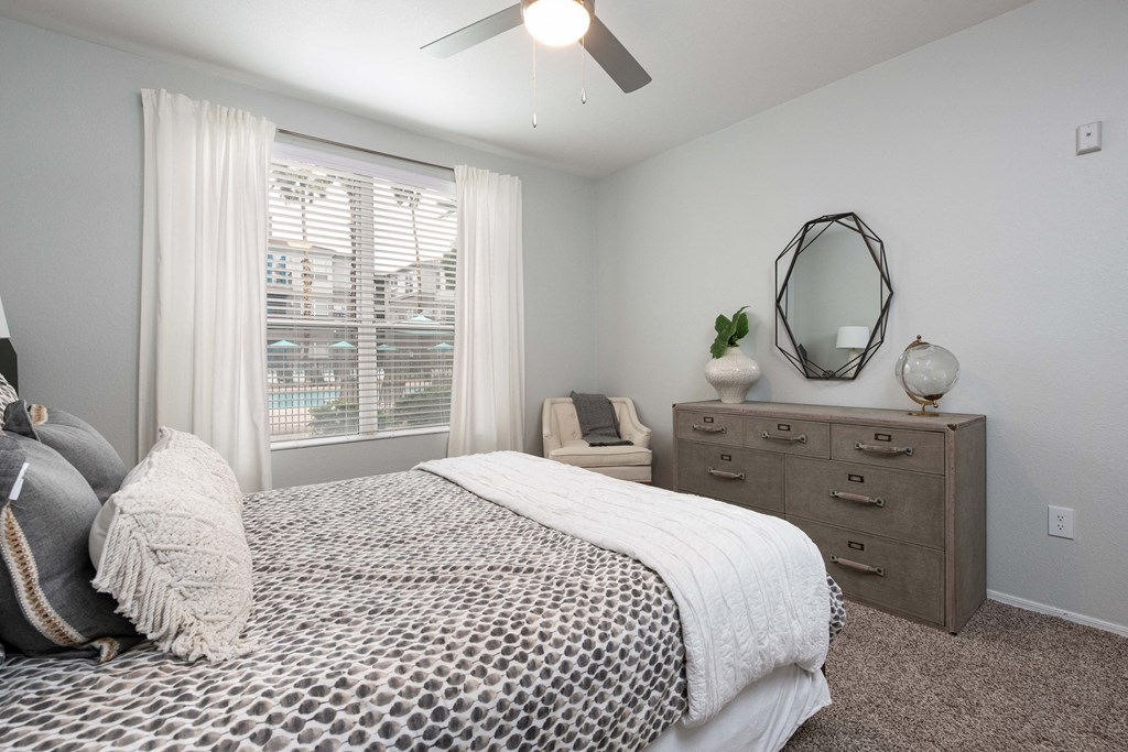 a bedroom with a large window and a bed and a dresser