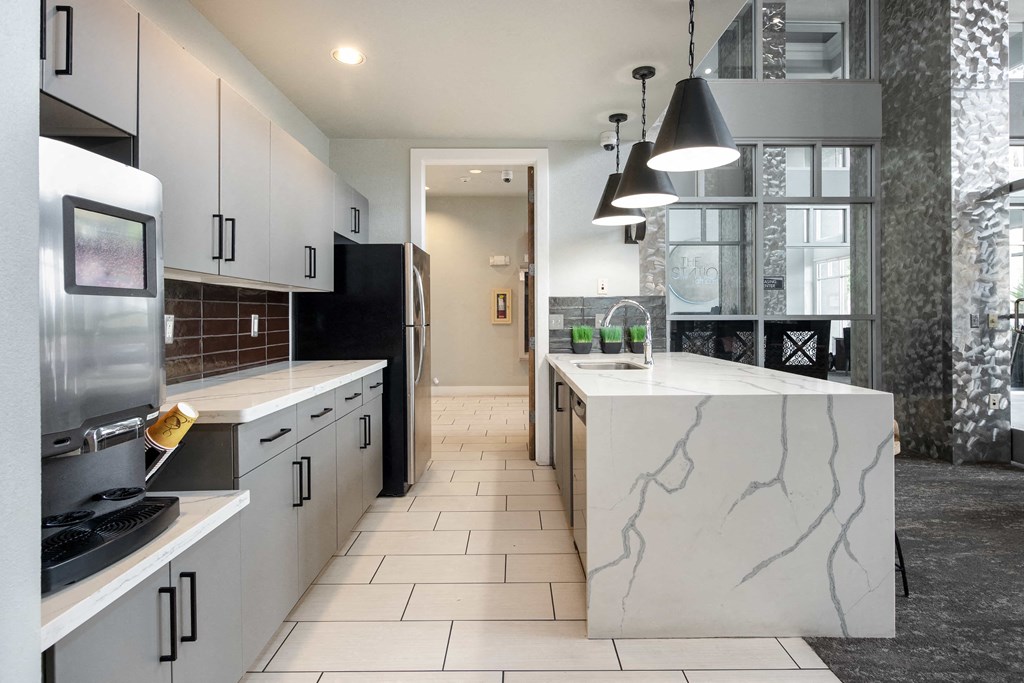 a kitchen with white cabinets and a marble counter top
