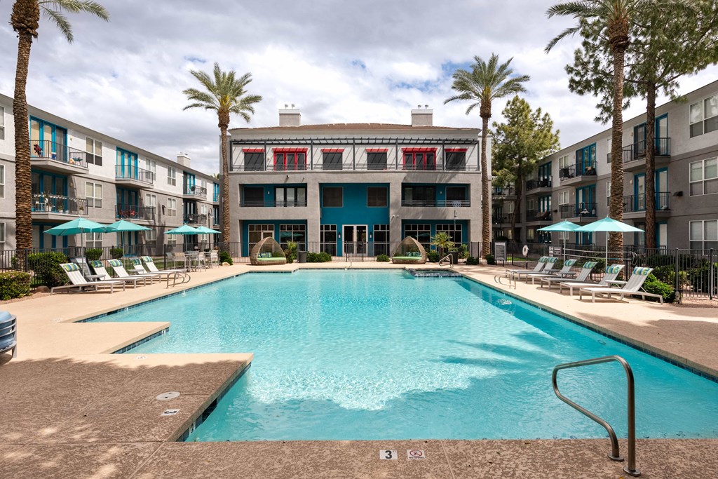 a swimming pool in front of a building with palm trees