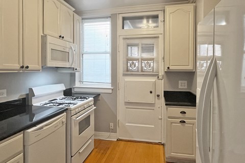 A kitchen with white cabinets and black countertops.