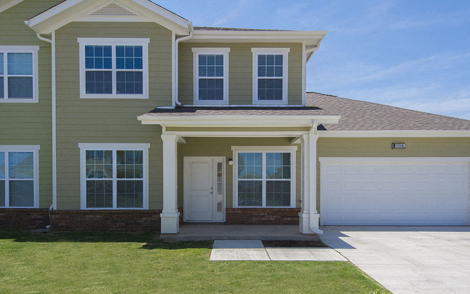 a beige house with a garage door and a lawn