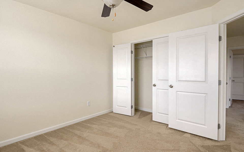 an empty bedroom with a closet and a ceiling fan