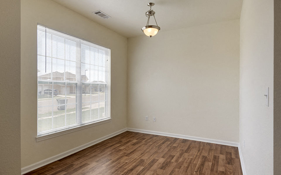 an empty living room with a large window and wood flooring
