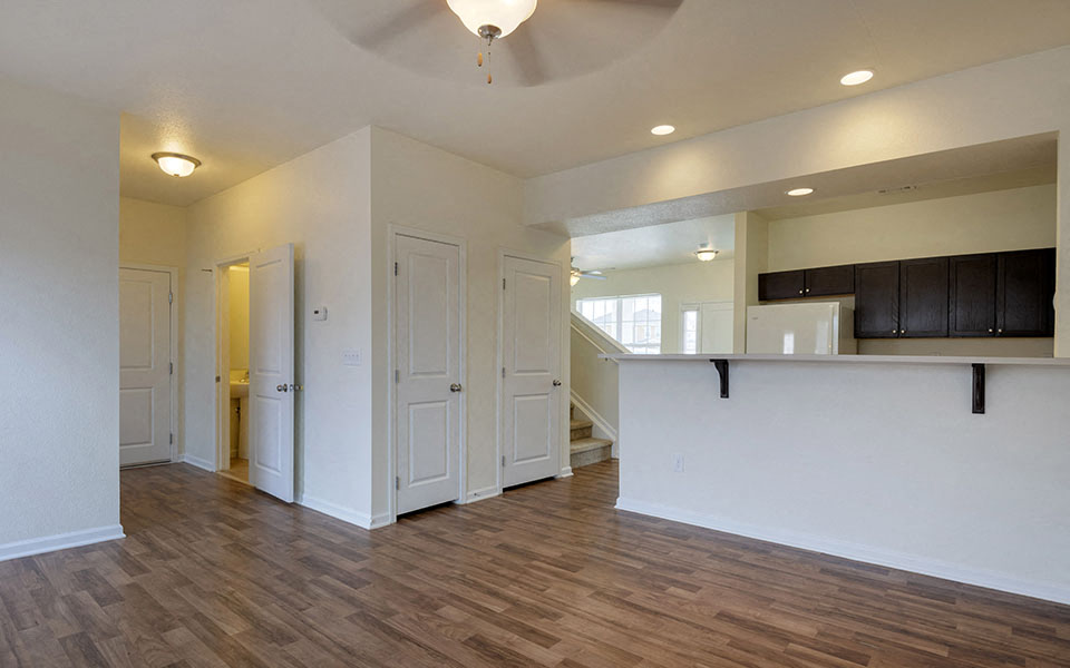 the living room and kitchen of a new home with white walls and wood floors