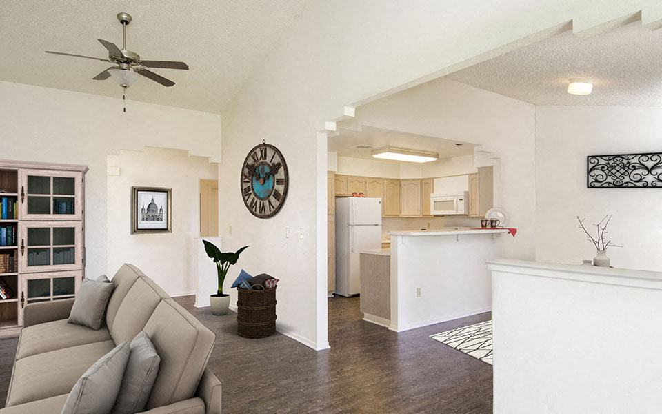 a living room and kitchen with a couch and a ceiling fan