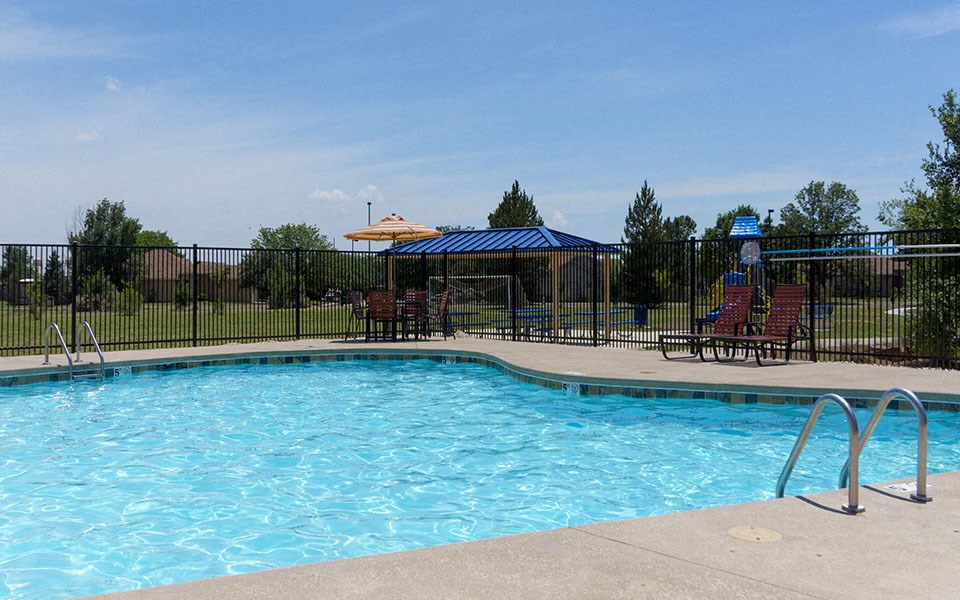a swimming pool with chairs and a fence around it
