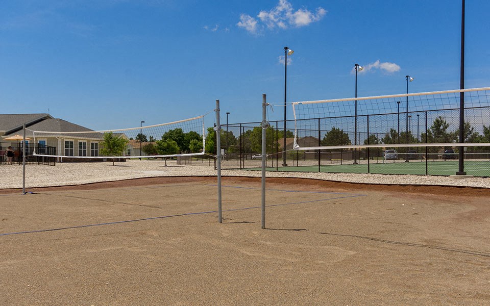 a tennis court with a fence around it and a house in the background