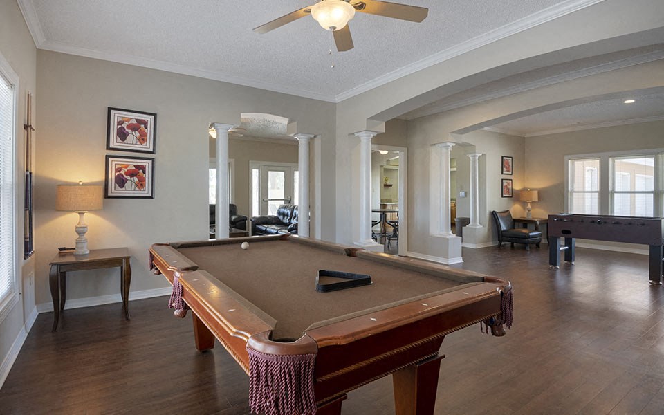 a pool table in a living room with a ceiling fan