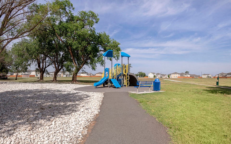 a playground with a blue and yellow swing set on a path