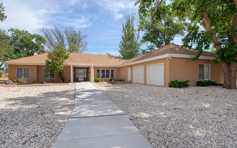 a house with a driveway and trees in front of it