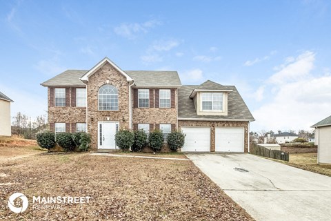 a brick house with two garage doors and a gravel driveway