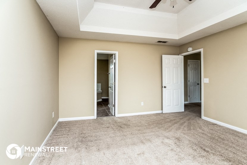 an empty living room with carpet and a ceiling fan