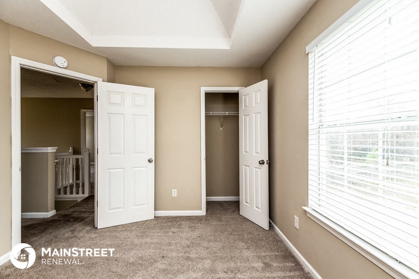 the master bedroom has a large window and carpeted flooring