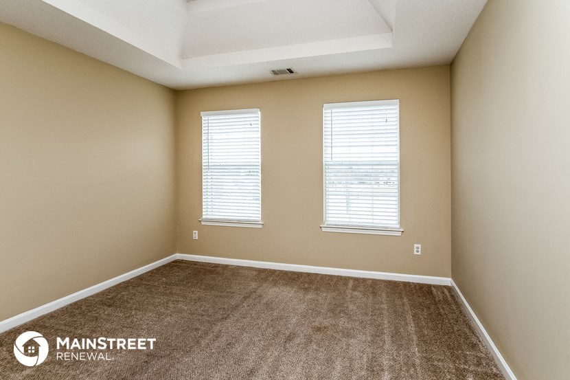 the upstairs bedroom with carpet and two windows