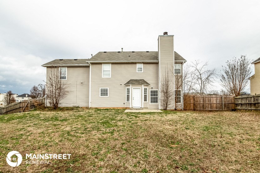 the back of a house with a yard and a fence
