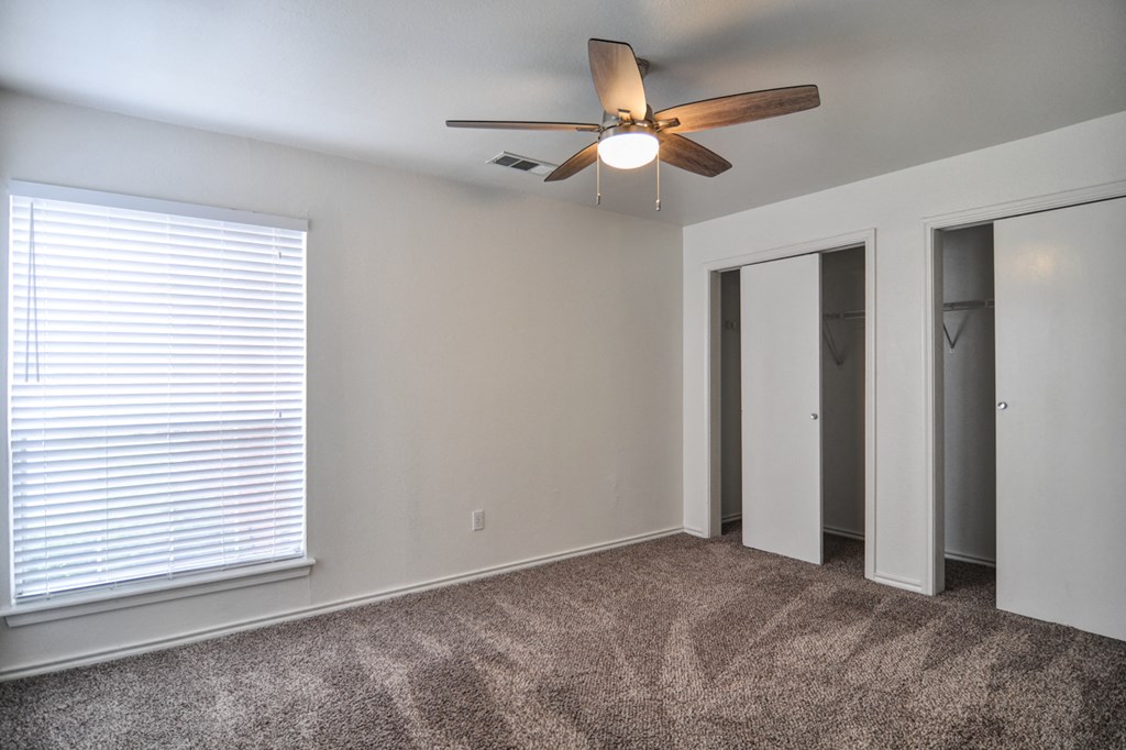 an empty room with a ceiling fan and a window