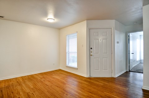 an empty living room with wood floors and a white door