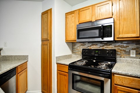a kitchen with a stove and microwave and wooden cabinets