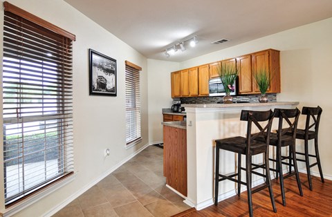 a bar with three stools in a kitchen with a large window