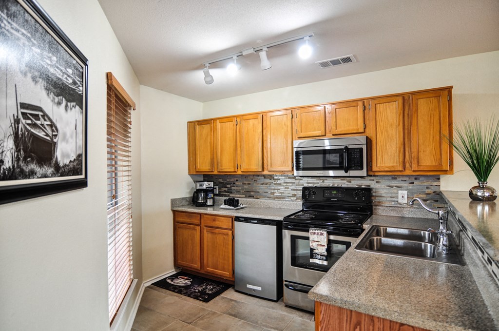 the kitchen has granite counter tops and stainless steel appliances and wood cabinets