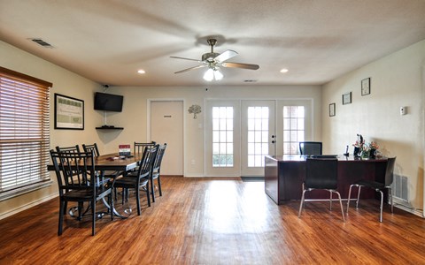 an empty living room with a dining room table and chairs and a ceiling fan