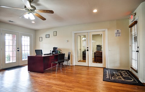 a living room with a desk and a ceiling fan