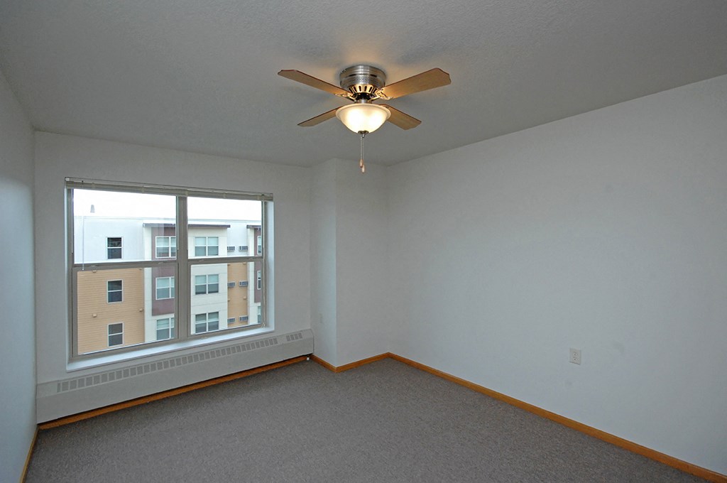 a bedroom with a large window and a ceiling fan