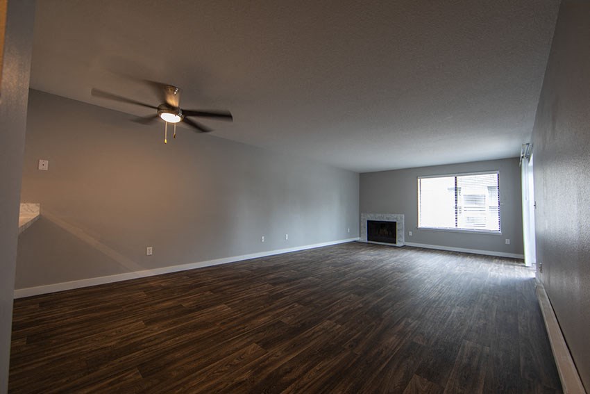 an empty living room with a ceiling fan and a window