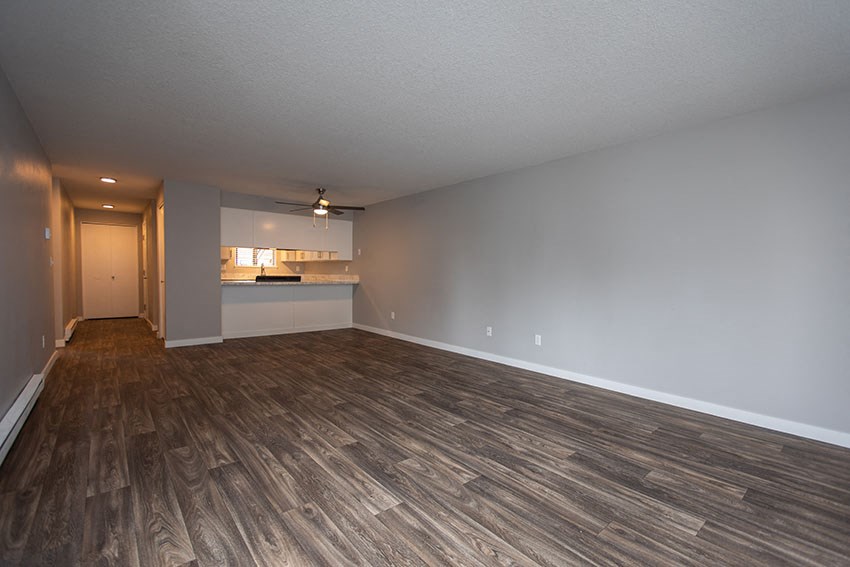 an empty living room and kitchen with wood flooring