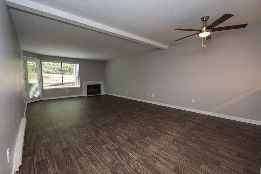 an empty living room with a ceiling fan and a window