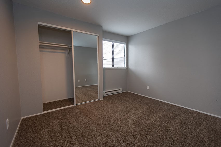 an empty bedroom with a closet and a window