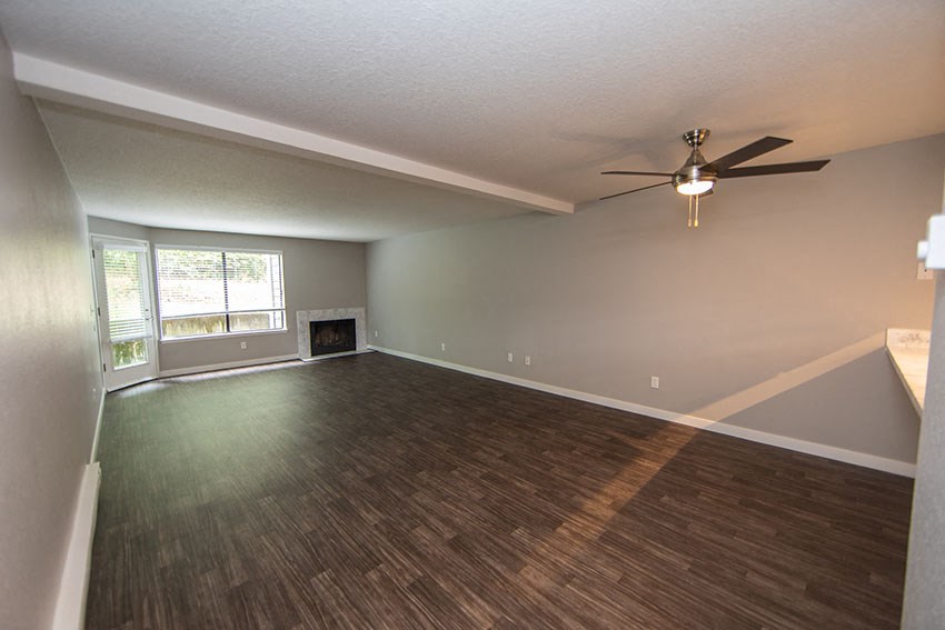 an empty living room with a ceiling fan and a window
