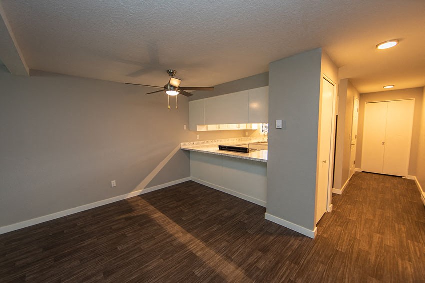 a empty living room and kitchen with a ceiling fan