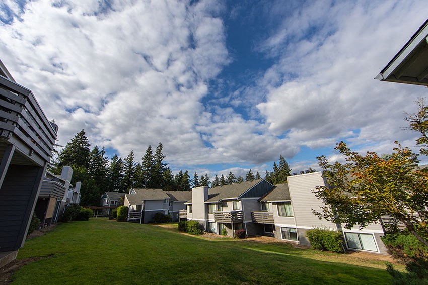 a row of houses on a green lawn with a cloudy sky
