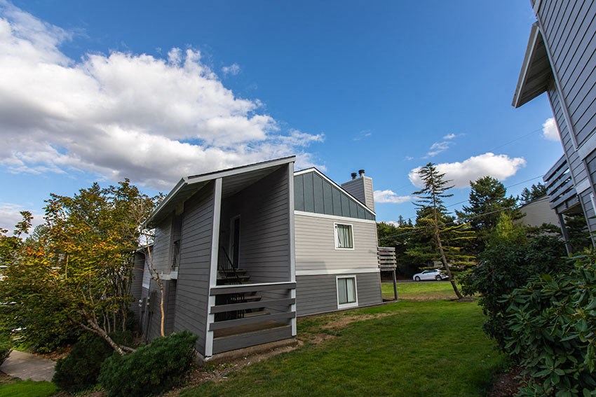 a small gray house with a porch on the side of