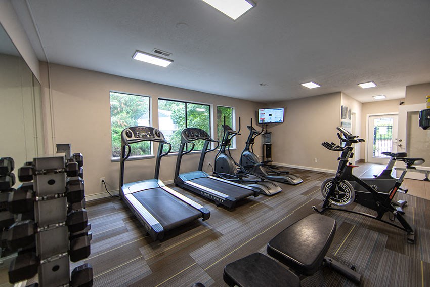 a gym with various exercise machines and a tv