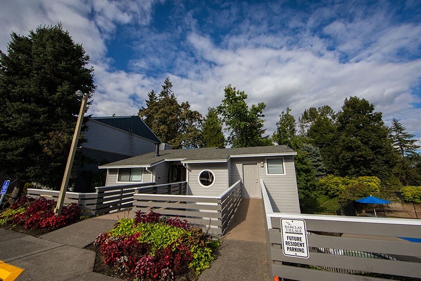 a small gray house with a porch and a sign on the front of it